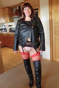 Amateur biker posing in leather jacket, red stockings and leather boots
