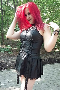 Redhead goth girl in leather dress and stockings in public place